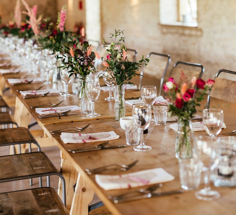 Neutral boho wedding tablescape with dried flower, rose, eucalyptus and foliage flower arrangements and off-white wedding menus and napkins with pink embroidery 