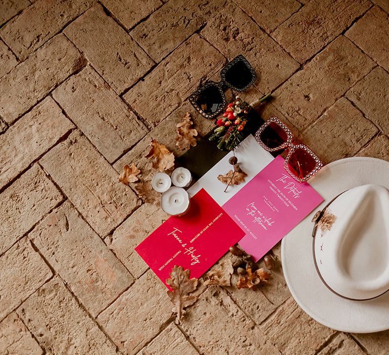 Bridal fashion accessories; white bridal fedora with black ribbon trim, large 60's inspired sunglasses, hot pink and baby pink wedding stationery, pillar candles and autumnal leaves 