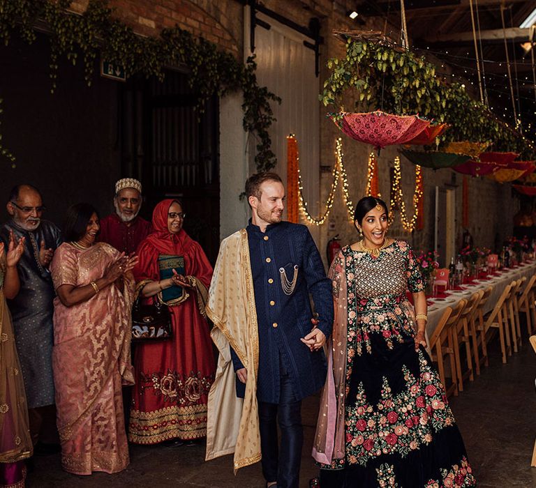 Bride & groom walk into wedding reception at Longbourn Estate Barn complete with colourful decor and fairy lights 