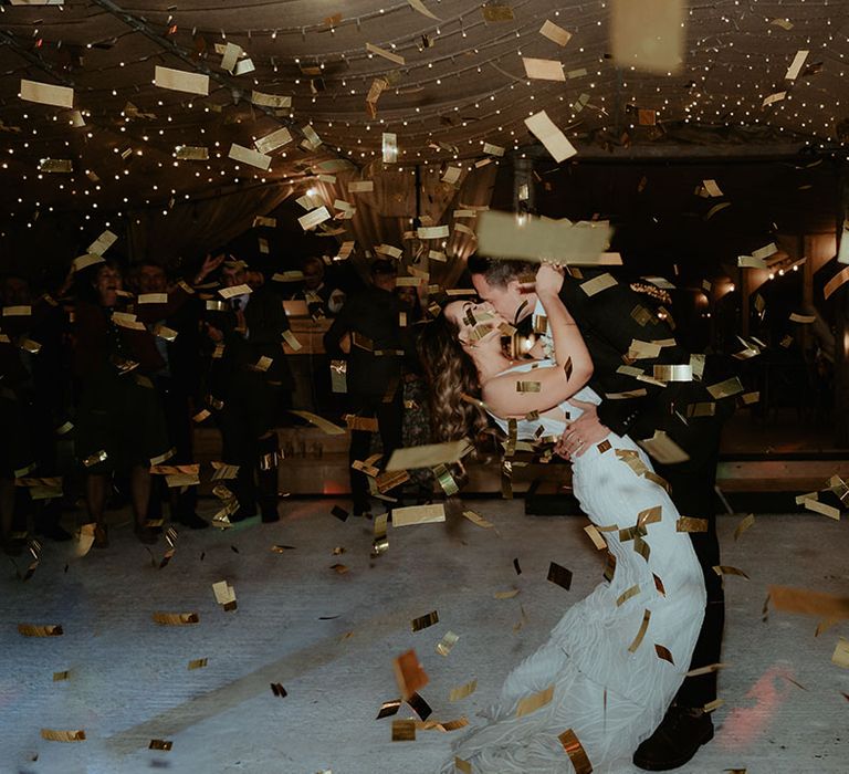 Gold confetti canon explodes as the bride and groom share their first dance together 