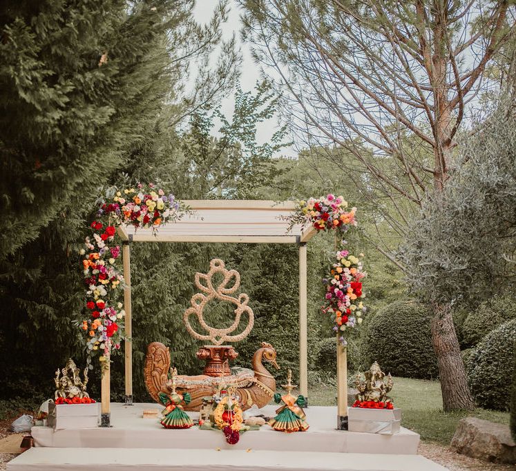 outdoor Hindu marriage ceremony with mandal decorated with colourful flowers 