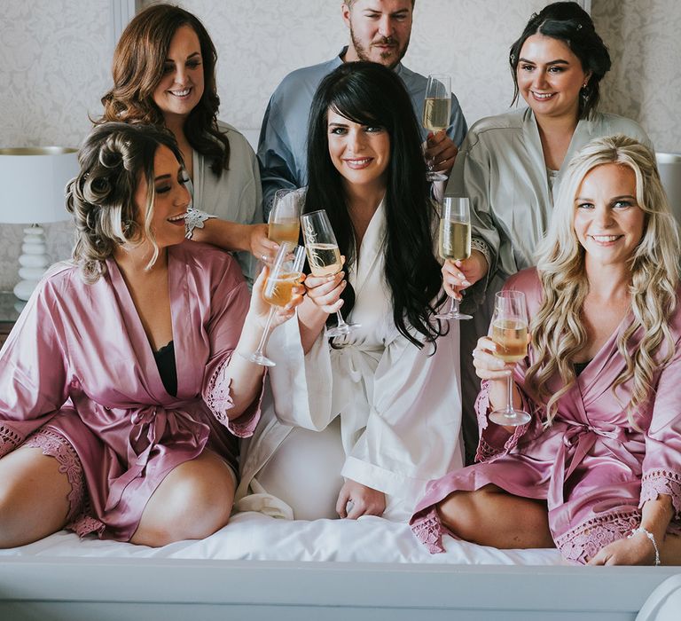 The bridal party with the bride in a white robe and party in pastel pink and green wedding robes with the bridesman in a blue robe