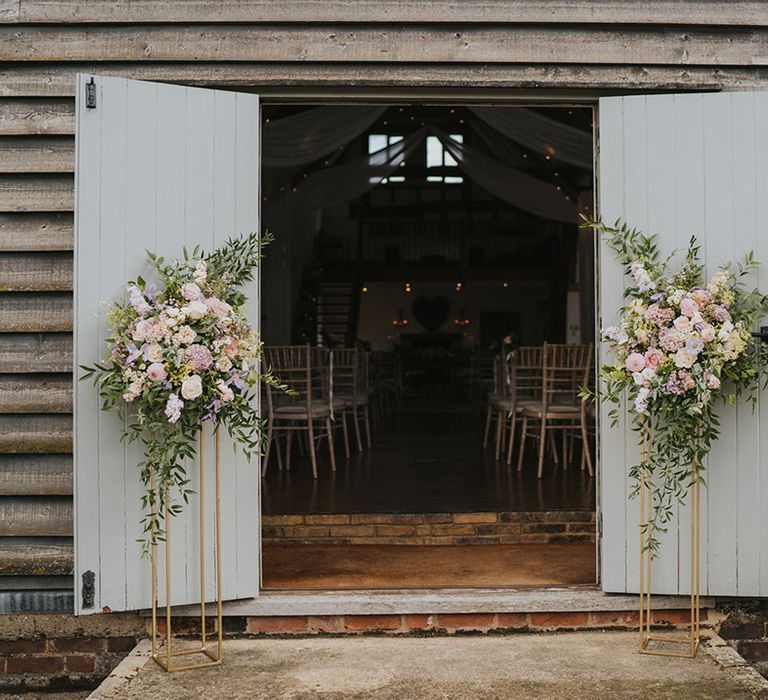 Pastel pink and lilac wedding flowers decorating the entrance to Dove Barn wedding venue 