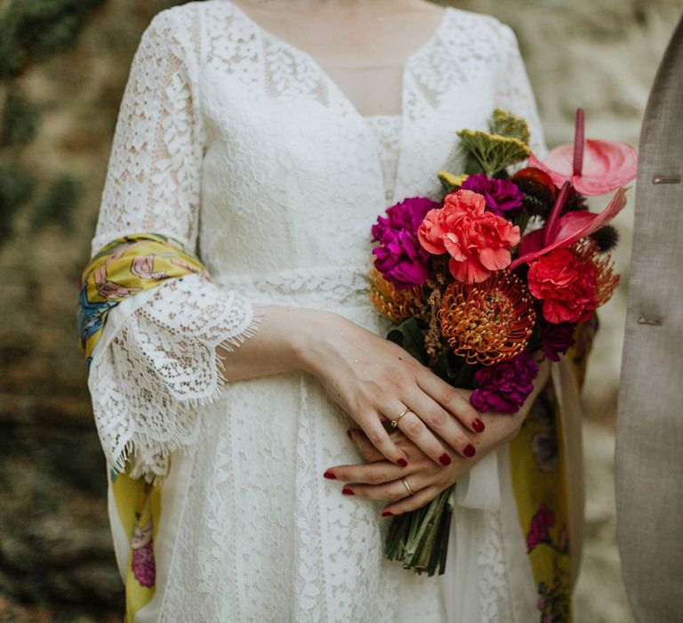 Bridal bouquet consisting of magenta peonies, coral carnations, pink anthuriums, and pincushion flowers