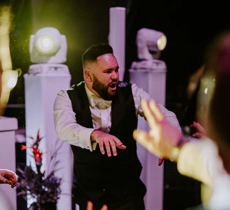 Groom in black waistcoat, white shirt and white bowtie dancing at nightclub-style wedding party at The Gherkin 