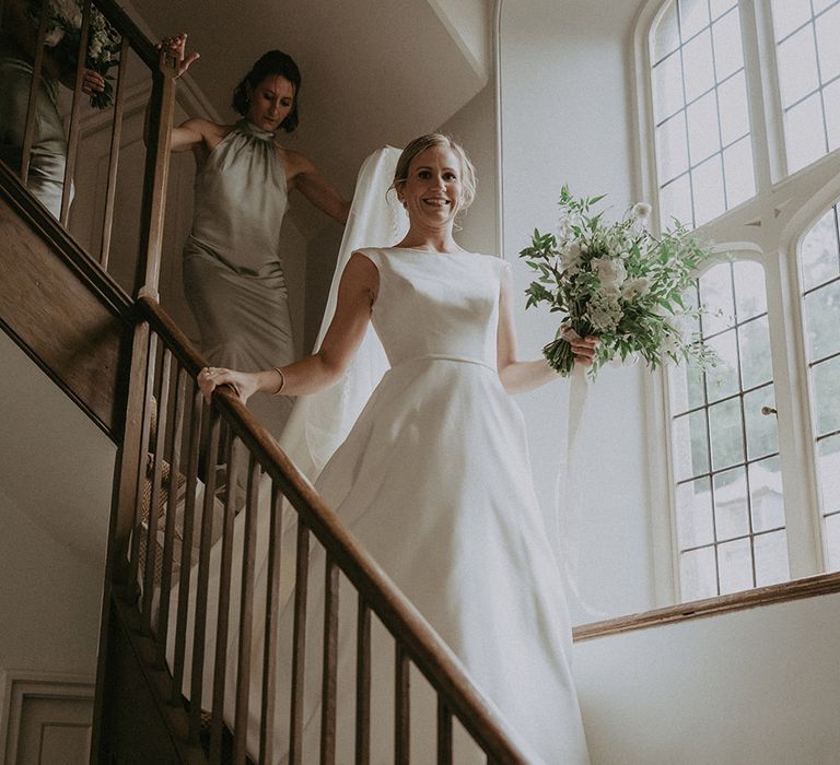 Bridesmaids in high neck sage green satin bridesmaid dresses walking down the stairs after the bride in a high neck San Patrick wedding dress 