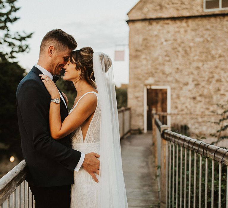 The bride and groom smile as they rest their foreheads against each other for a cute couple portrait 