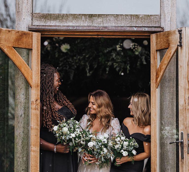 Bridal party in black bridesmaid dresses posing with the bride in a winter wedding dress for November wedding 