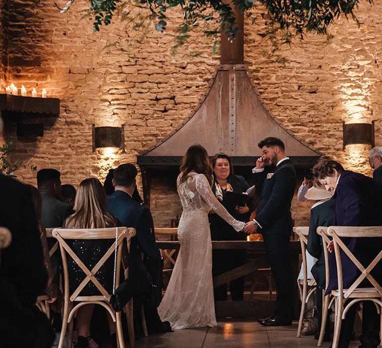 Groom in navy suit wipes his eyes as he cries during his civil ceremony at the rustic barn wedding venue 