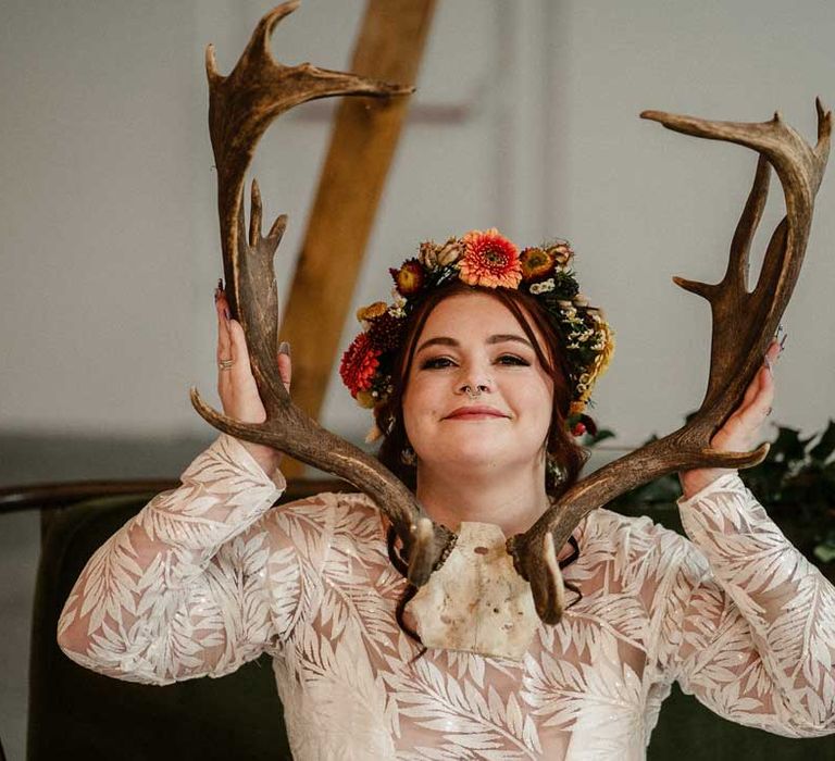 Bride in boho long sleeve 3D applique wedding dress with boho rustic dried flower crown holding up stag antlers 