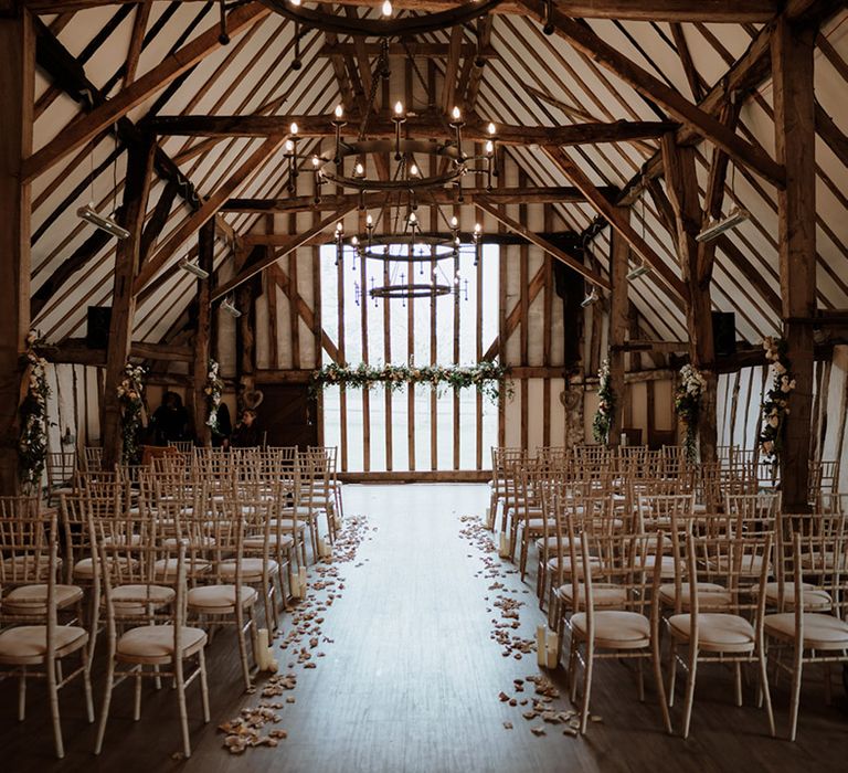 Colville Hall barn wedding venue in Essex with pillar candles and flower petals decorating the aisle 