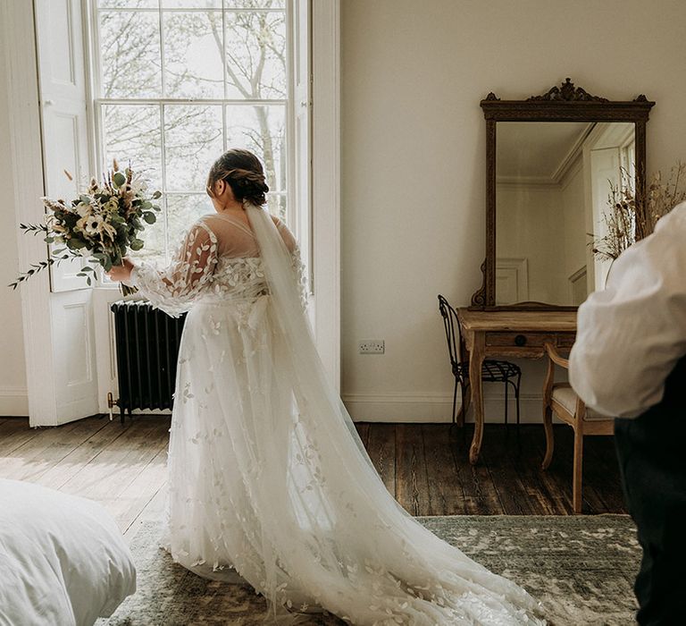 Bride in lace wedding dress with train preparing for first look with father of the bride 