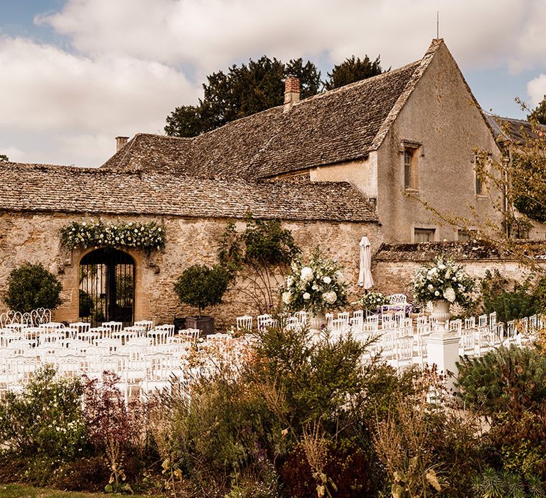 Caswell House Cotswold wedding venue with white chairs set up in the courtyard for the outdoor wedding ceremony 