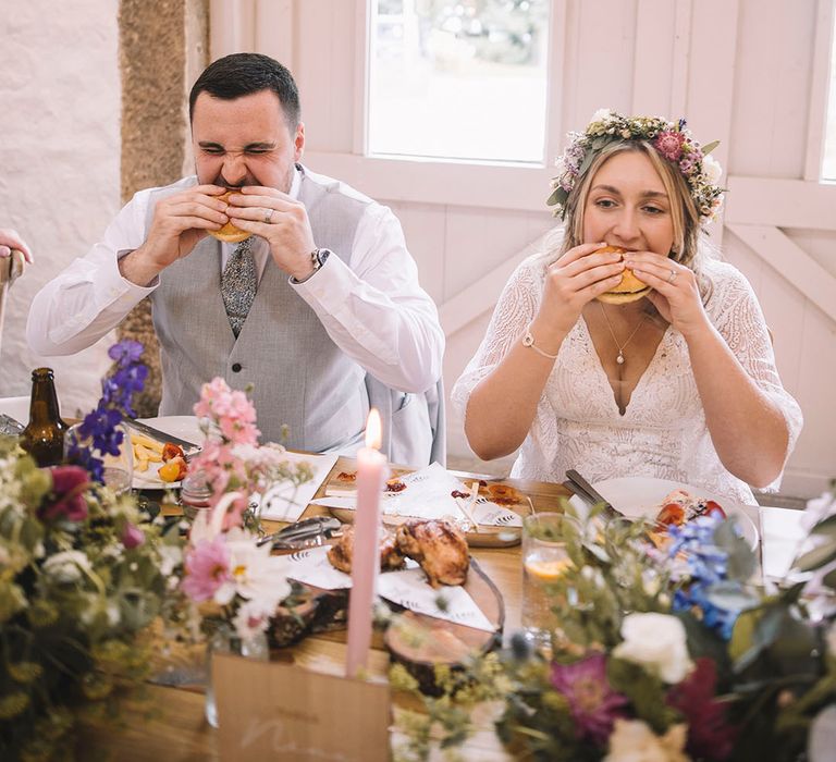 The bride and groom take bites into their burgers 