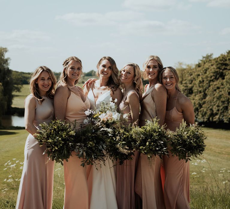 Bridal party posing wit the bride for stunning picture outdoors 