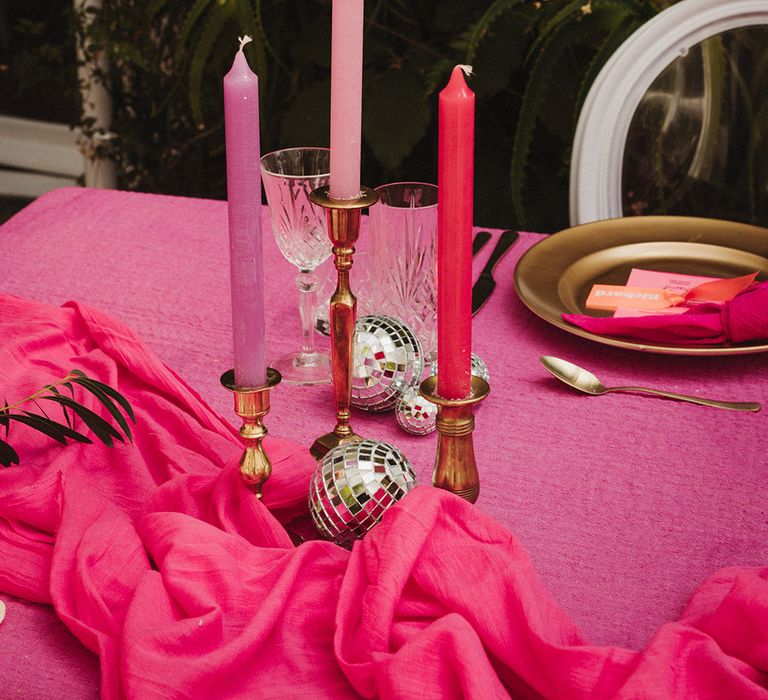 Purple, pink and hot pink candles decorating the wedding table with crystal glassware