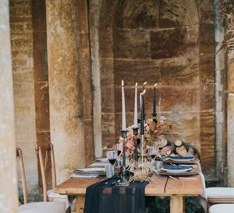 Black table runner over wooden table with black taper candles 