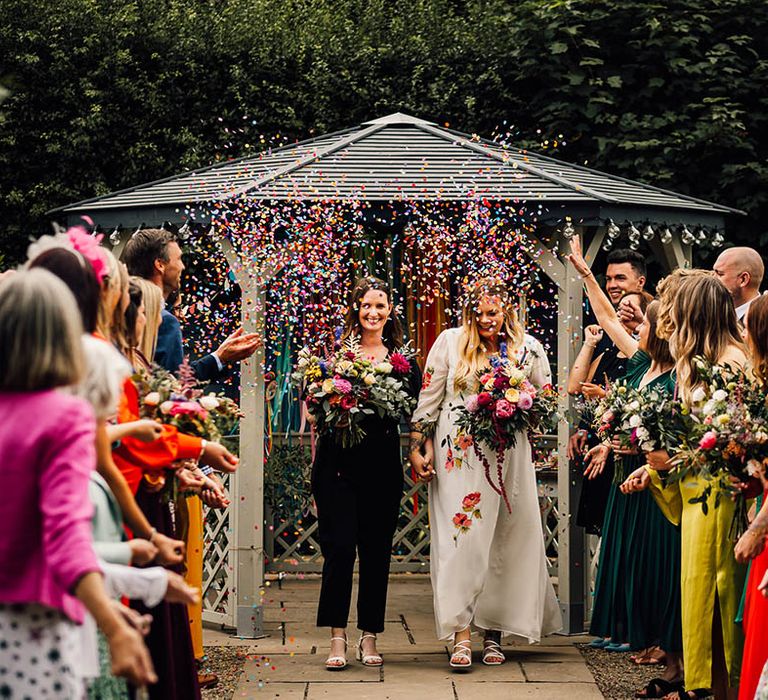 Rainbow colourful confetti moment for two brides as they exit from their same sex wedding ceremony 