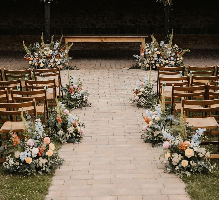 Blue, yellow, pink and orange pastel wedding flower decorations along the aisle and altar 