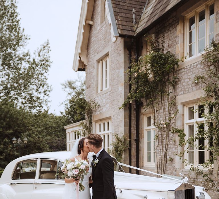 Rolls Royce cream wedding car with the bride in a satin wedding gown with the groom in black tie 