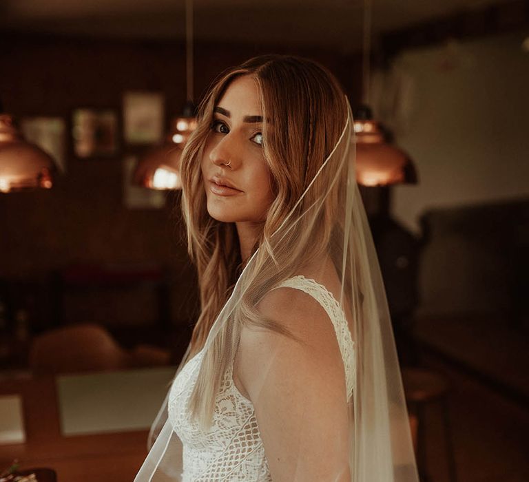 Bride wearing boho lace wedding dress and fingertip length veil 