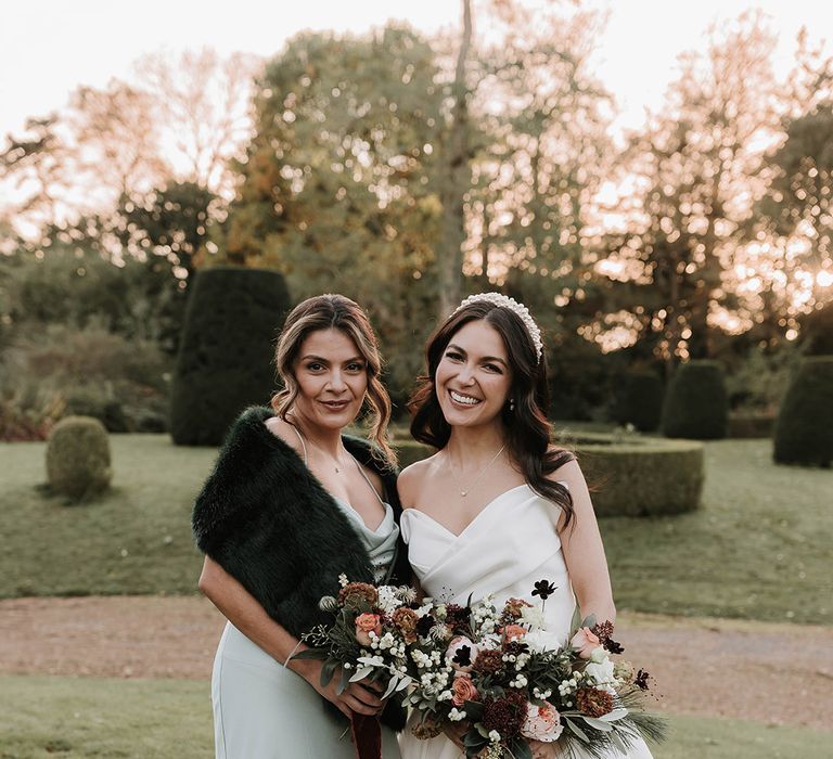 Bridesmaid in satin mint green bridesmaid dress and faux fur shawl with the bride 