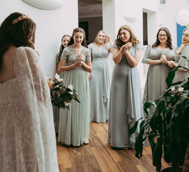 Bridesmaids in mismatched green bridesmaid dresses seeing the bride for the first time 