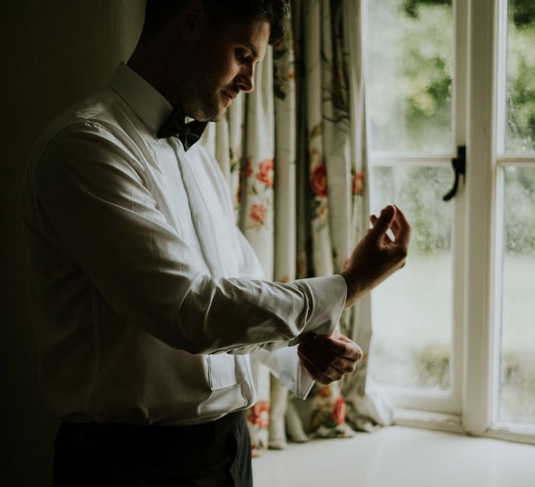 Groom does up his cufflinks as he gets ready for the wedding 