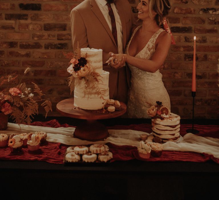 Bride and groom standing next to the dessert table 