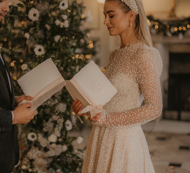 Bride in long sleeve sparkly wedding dress reading her vows at Gosfield Hall