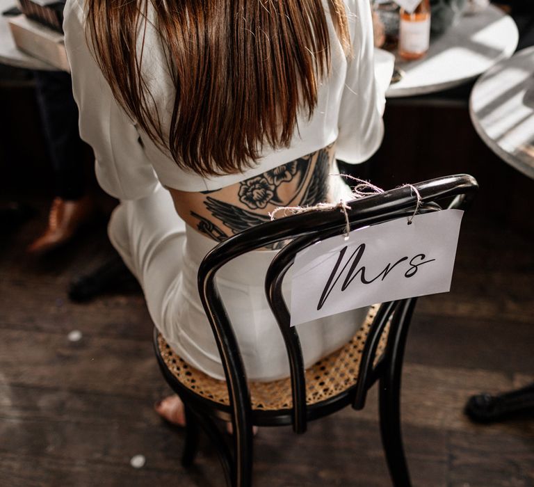 open back bridal jumpsuit sitting at her Chair 