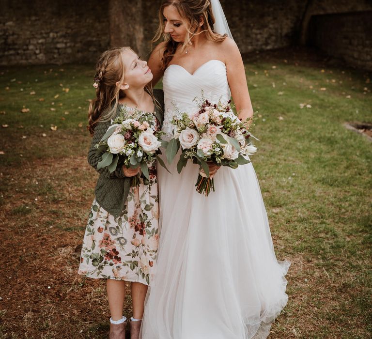 Bride in a strapless wedding dress with her daughter in a floral dress 