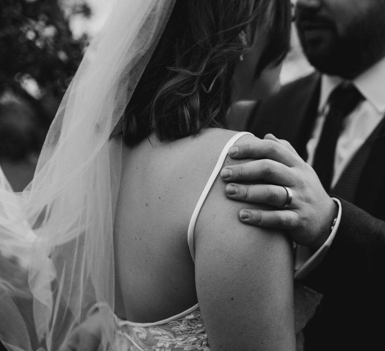 Groom with wedding ring hugging bride