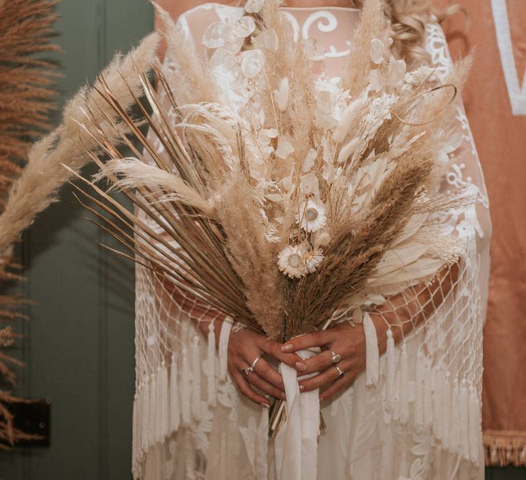 Bride holds dried flowers and pampas grass bouquet at wedding reception