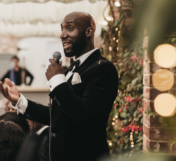 Black groom in a velvet tuxedo and bow tie giving his wedding speech at the Northbrook Park reception 