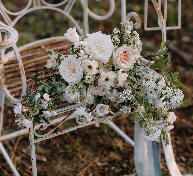 The wedding bouquet on top of rustic garden seating