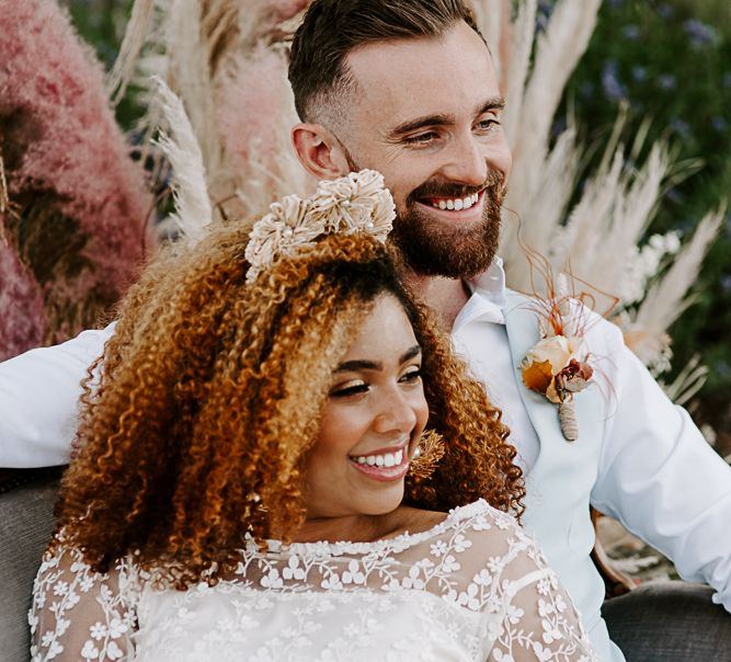 Bride leans back on groom whilst smiling during wedding day