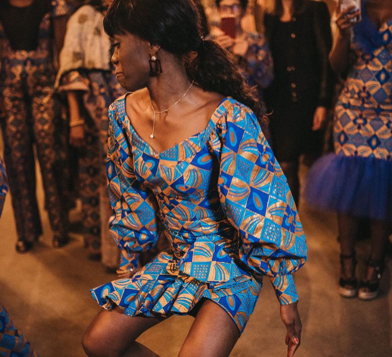 Wedding guest in a blue and gold West African print outfit 