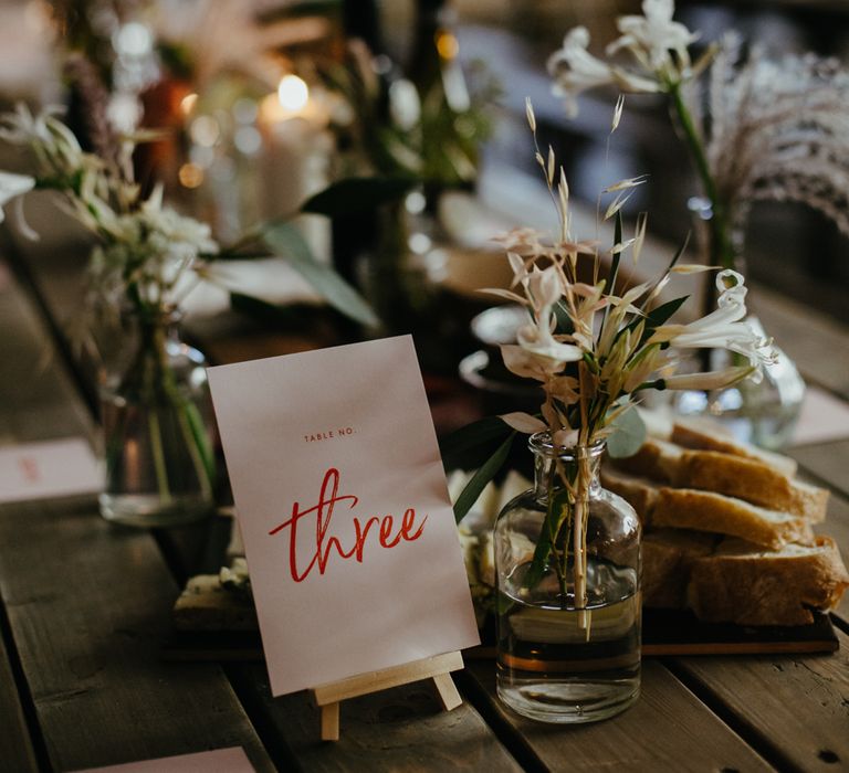 Table no. Three sign and bud vase on trestle table next to rustic bread