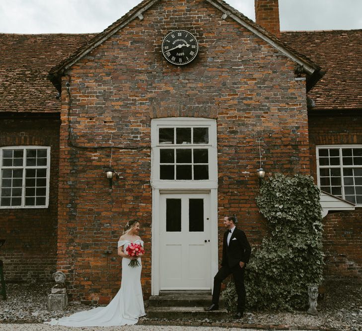 Bride & groom stand between large white door 