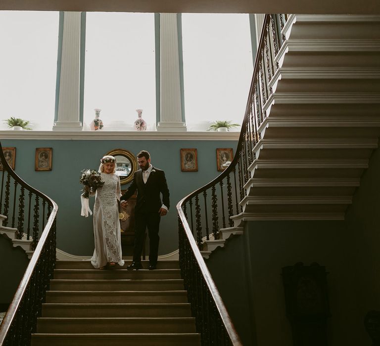 Bride in Grace Loves Lace wedding dress and single tier cathedral length veil walks down stairs with groom in black Hugo Boss suit at Drenagh Estate Wedding