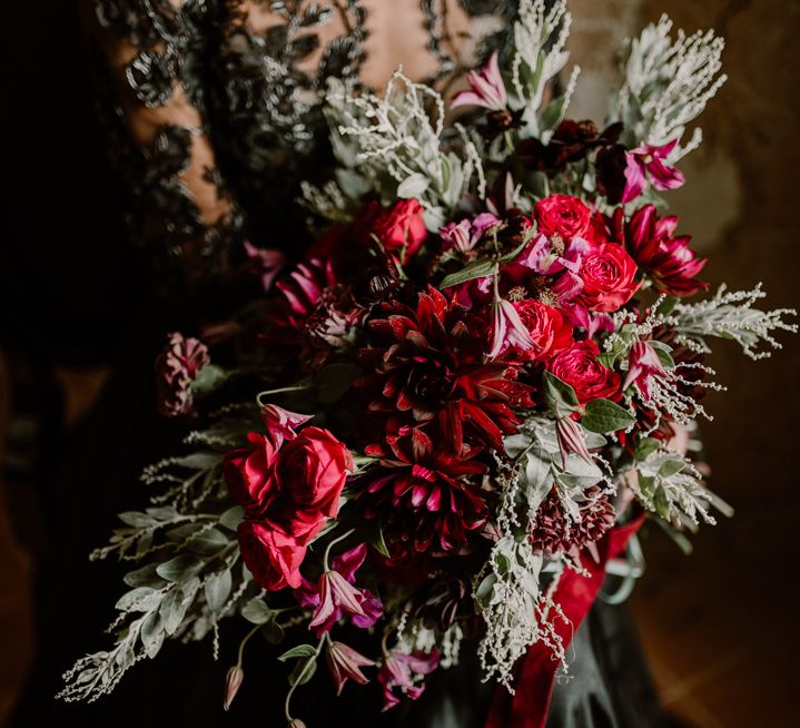 Deep red flowers and green foliage wedding bouquet tied with ribbon