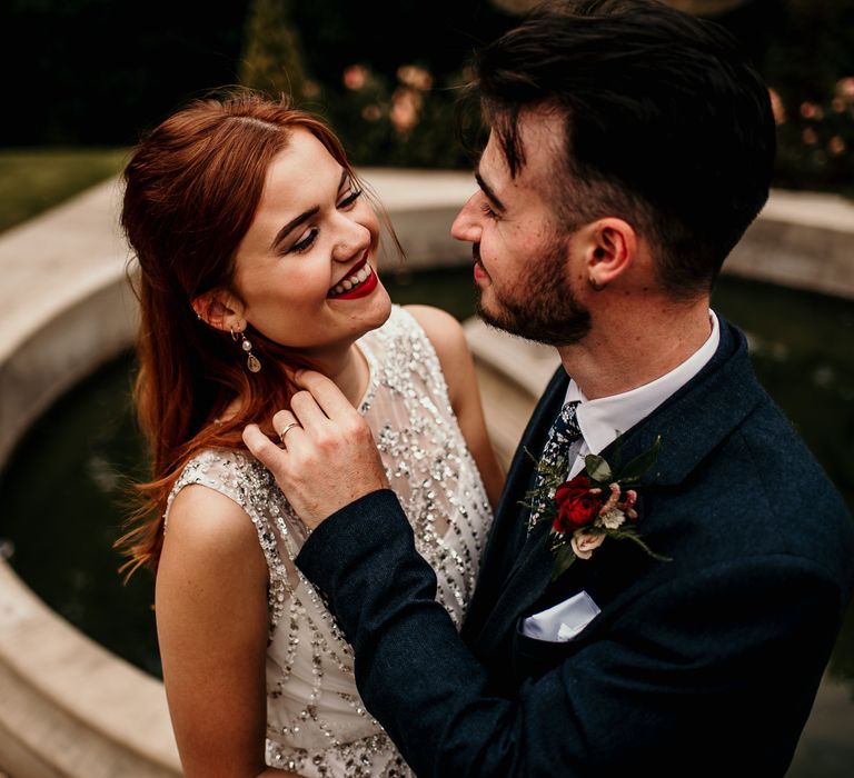 Bride & groom look lovingly into one another's eyes beside fountain