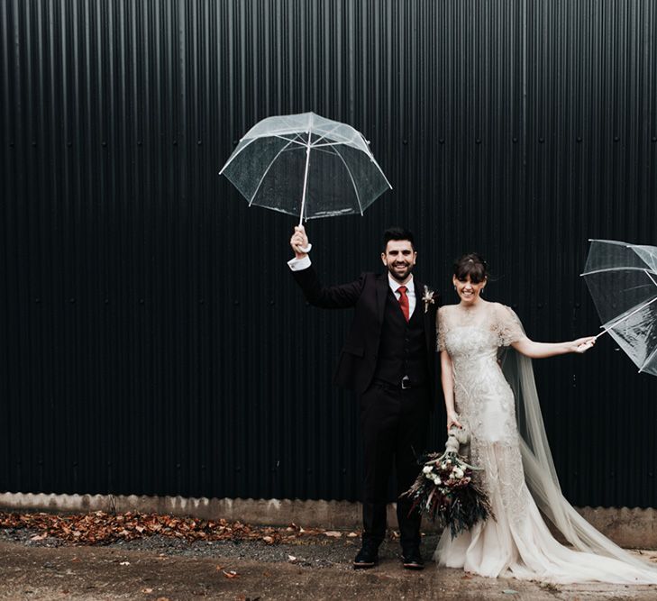 A bride and groom play with umbrellas during their wedding portraits.