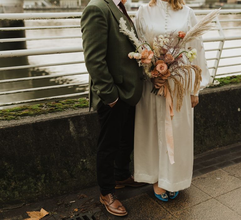 Bride & groom stand together as bride holds floral bouquet