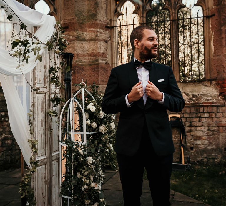 Groom in a black tuxedo standing at the altar of St Lukes' bombed out church in Liverpool 