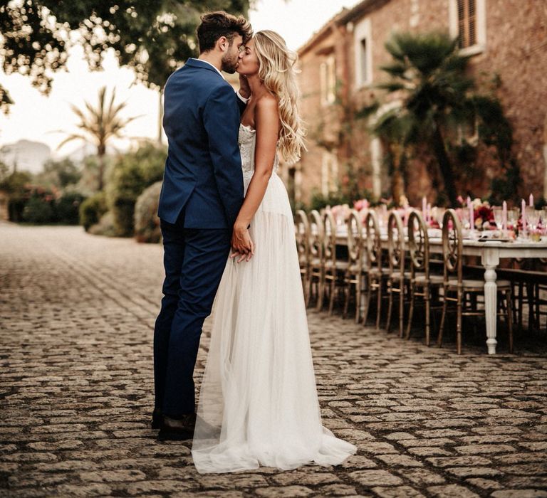 Bride and groom kiss next to exquisite banquet table for finca wedding in Spain