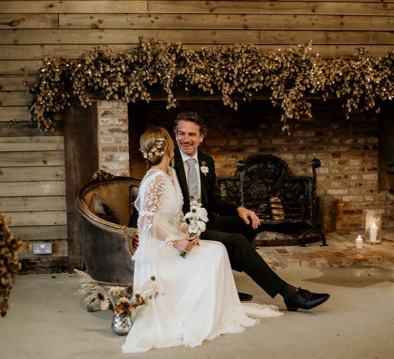 Bride and groom sat at rustic luxe wedding ceremony with neutral foliage decor