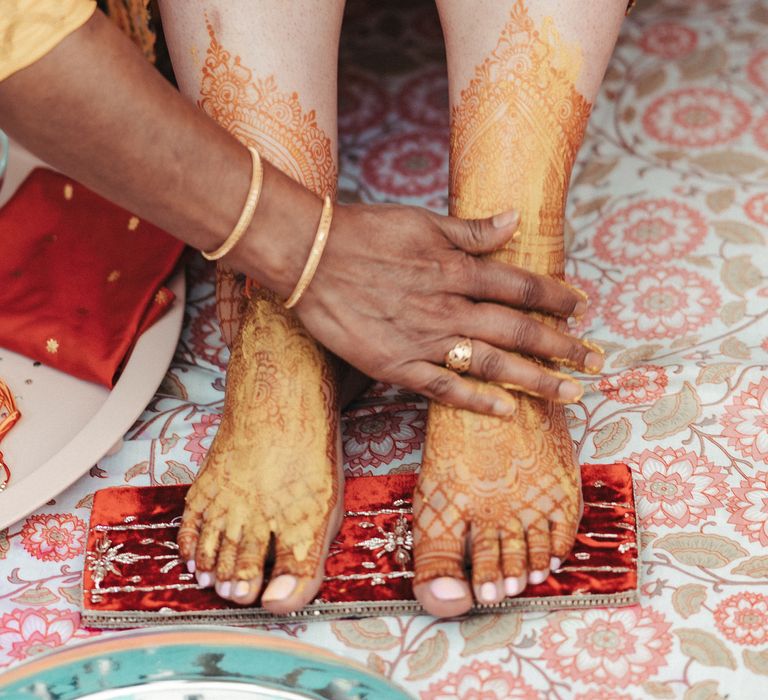 Bride as her feet covered in turmeric during Haldi wedding ceremony