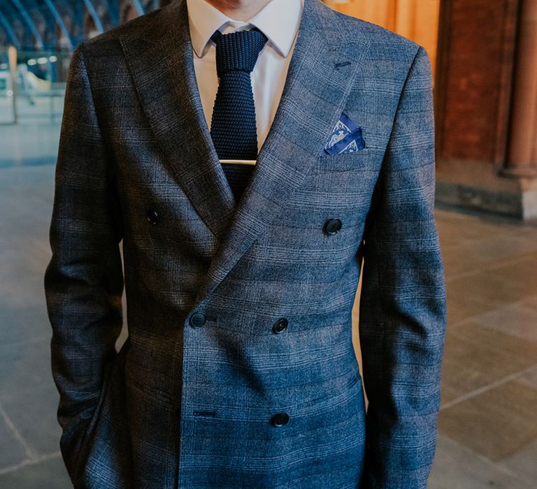 Groom wears dapper grey suit with silk pocket square, navy blue tie and silver pin 